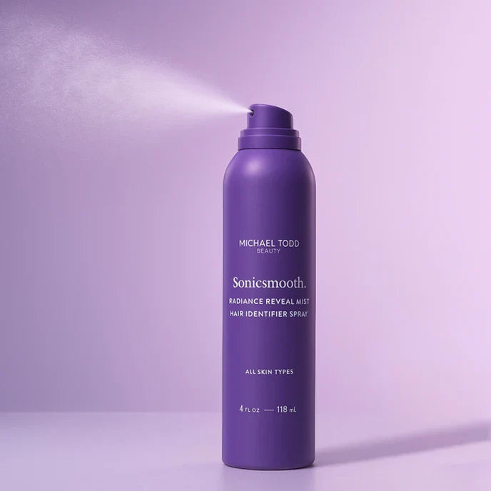 A purple spray can labeled "Michael Todd Beauty Dermaplaning Essentials Kit" dispenses mist against a light purple background.