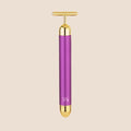 Michael Todd Beauty's Gold Bar facial massage tool features a T-shaped handle with purple and gold accents, set against a beige background.