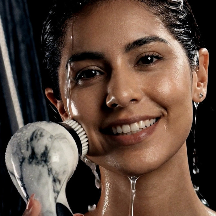 A woman smiling in the shower while using a Michael Todd Beauty Hydrojet handheld shower system.