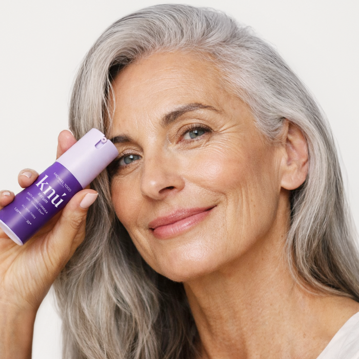 A woman is holding a bottle of Knú Serum by Michael Todd Beauty.